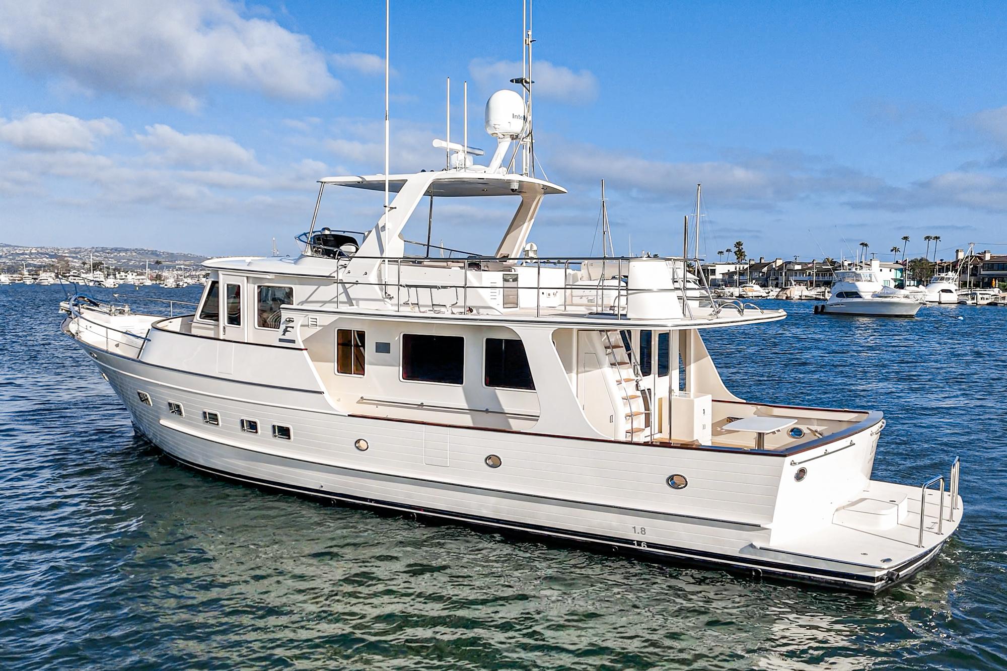 2018 Fleming 58 Pilothouse yacht on calm water under blue sky.