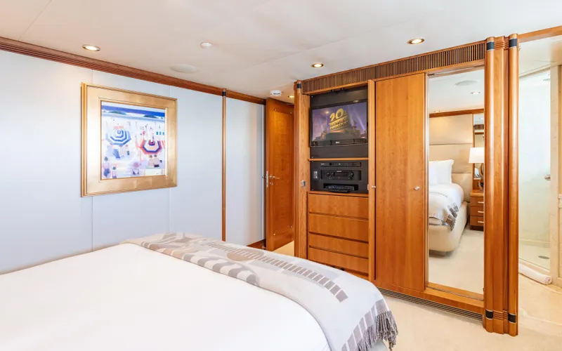 Sea Class Yacht Photos Pics Luxurious yacht bedroom with wooden decor, cozy bed, and framed artwork, Christensen 1997 model.