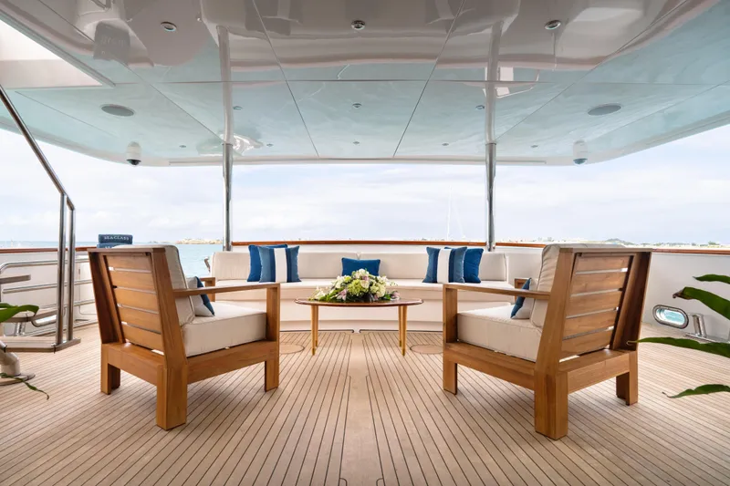 Sea Class Yacht Photos Pics Luxurious yacht deck with wooden furniture, blue cushions, and floral centerpiece, Christensen 1997 model.