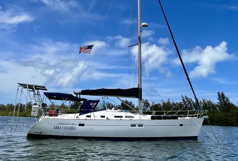 Abra Cadabra Yacht Photos Pics 2004 Beneteau Oceanis 423 sailboat on water, clear sky, American flag flying.