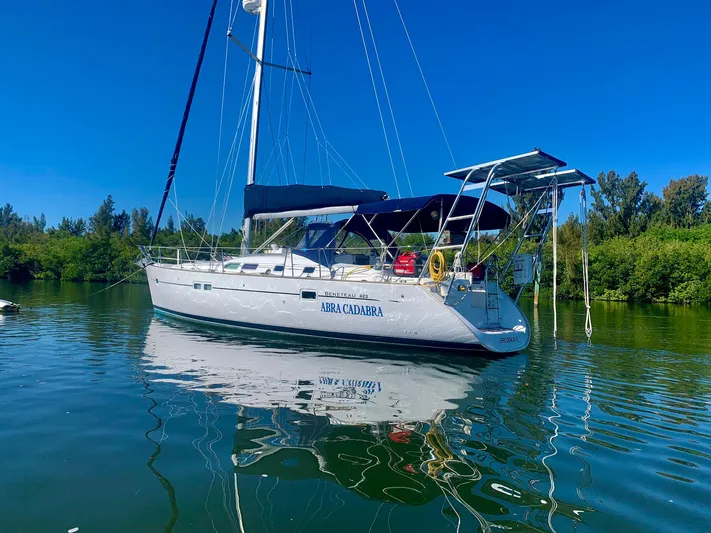 Abra Cadabra Yacht Photos Pics 2004 Beneteau Oceanis 423 sailboat on calm water, surrounded by lush greenery.