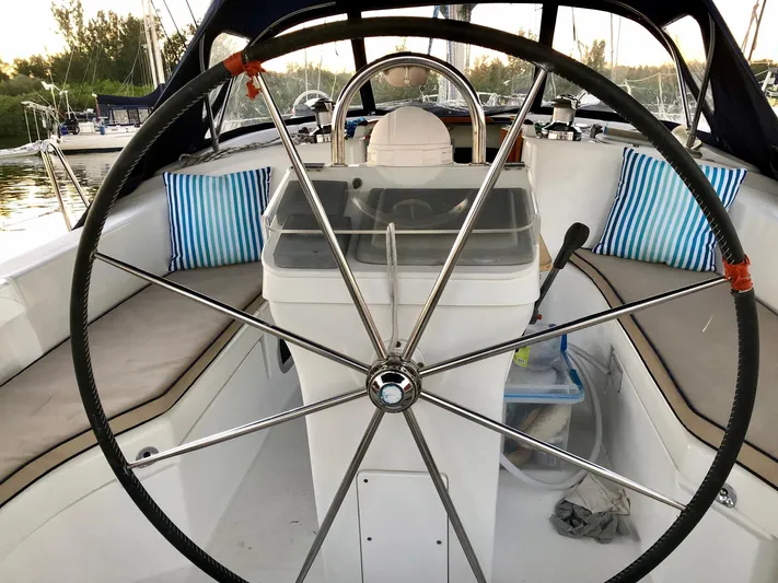 Abra Cadabra Yacht Photos Pics Cockpit of 2004 Beneteau Oceanis 423 sailboat with large steering wheel and striped cushions.