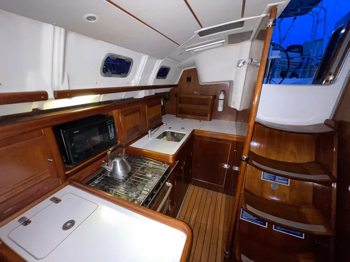 Abra Cadabra Yacht Photos Pics Interior of 2004 Beneteau Oceanis 423 sailboat, featuring a well-equipped kitchen and wooden cabinetry.