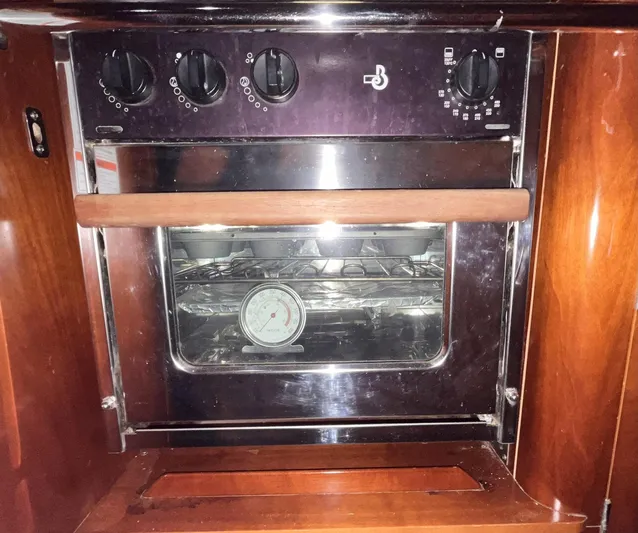 Abra Cadabra Yacht Photos Pics Built-in oven on 2004 Beneteau Oceanis 423 yacht, featuring temperature gauge and wooden accents.