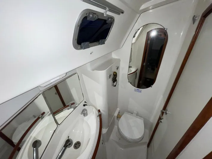 Abra Cadabra Yacht Photos Pics Beneteau Oceanis 423 2004 yacht bathroom with sink, mirror, and toilet.