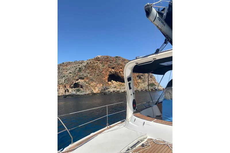  Yacht Photos Pics Sailing on a 2000 Hunter 45 Center Cockpit near rocky coastal cliffs under clear blue skies.