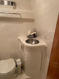 Compact bathroom in a 2003 Regal 2765 boat, featuring a sink and toilet.