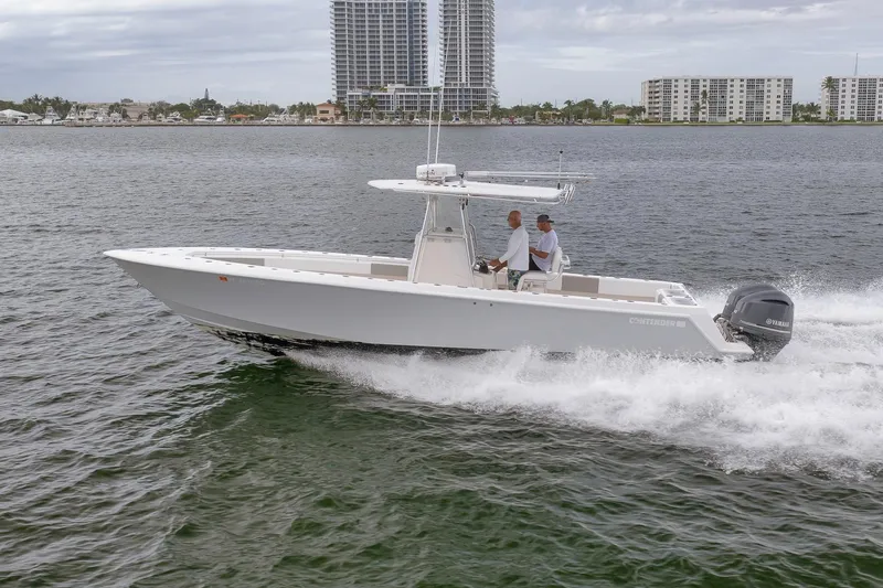  Yacht Photos Pics 2012 Contender 32 Tournament boat cruising on water with cityscape background.
