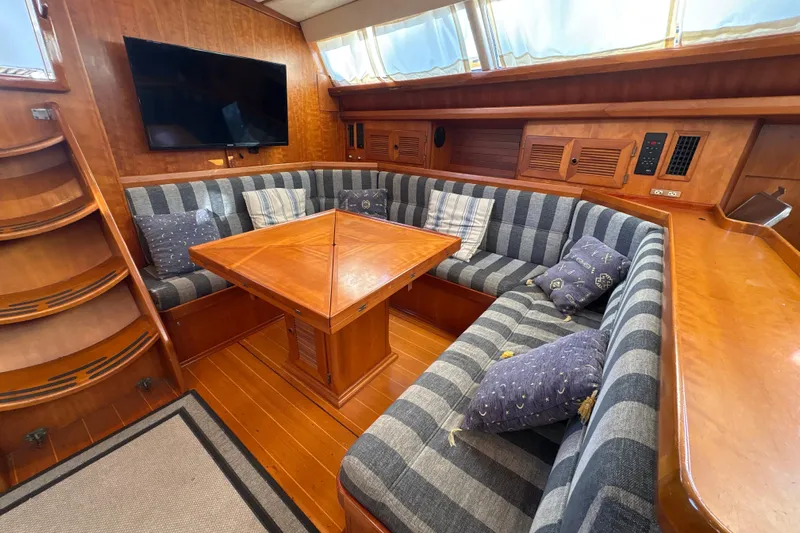 Ganymede Yacht Photos Pics Luxurious North Wind 56 yacht interior with striped seating, wooden table, and mounted TV, 2001 model.