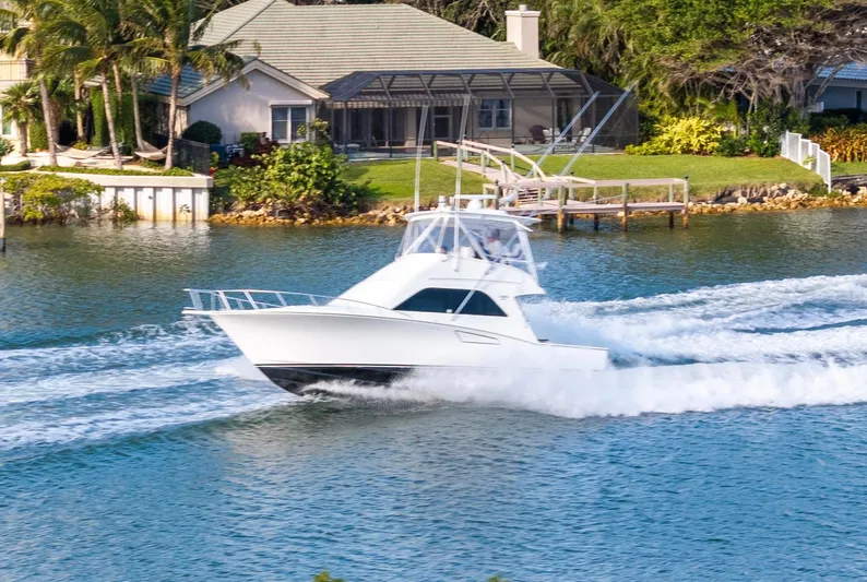 Well Played Yacht Photos Pics Cabo 40 Flybridge 2011 cruising on a scenic waterway near a waterfront home.