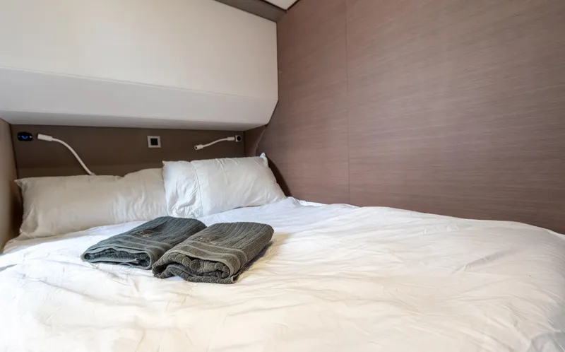 Cinders Yacht Photos Pics Cozy cabin bed with white linens and folded towels in a 2020 Bali 5.4 model.