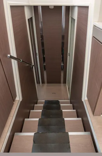 Cinders Yacht Photos Pics Staircase inside 2020 Bali 5.4 yacht, featuring sleek wooden design and modern handrail.