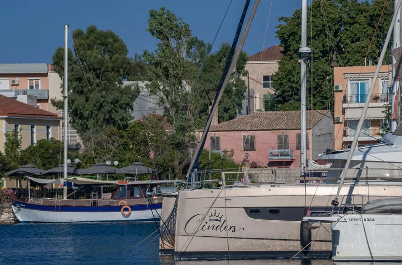 Cinders Yacht Photos Pics Catamaran Bali 5.4 docked in a scenic harbor with colorful buildings and trees.