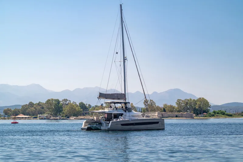 Cinders Yacht Photos Pics Sailing catamaran Bali 5.4, 2020 model, on serene water with mountainous backdrop.