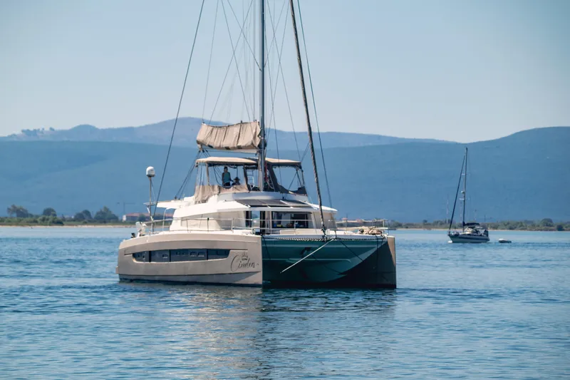 Cinders Yacht Photos Pics 2020 Bali 5.4 catamaran sailing on calm waters with distant hills in the background.