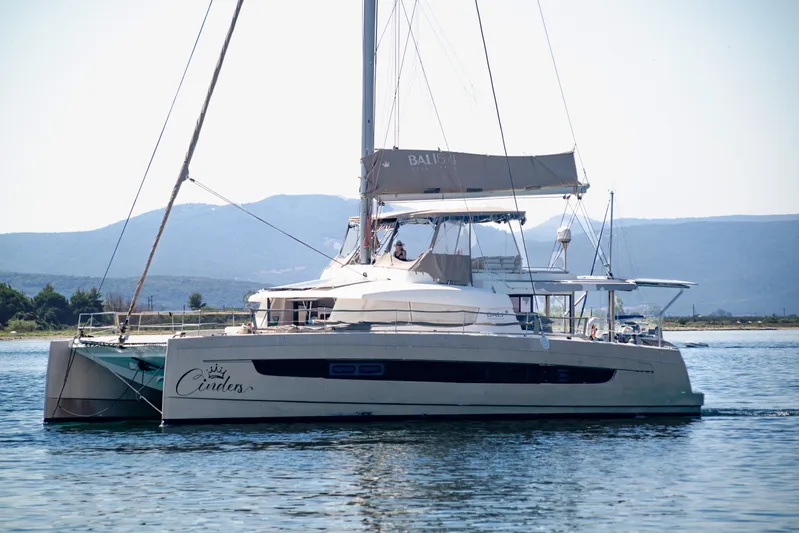 Cinders Yacht Photos Pics 2020 Bali 5.4 catamaran sailing on calm waters with mountainous backdrop.