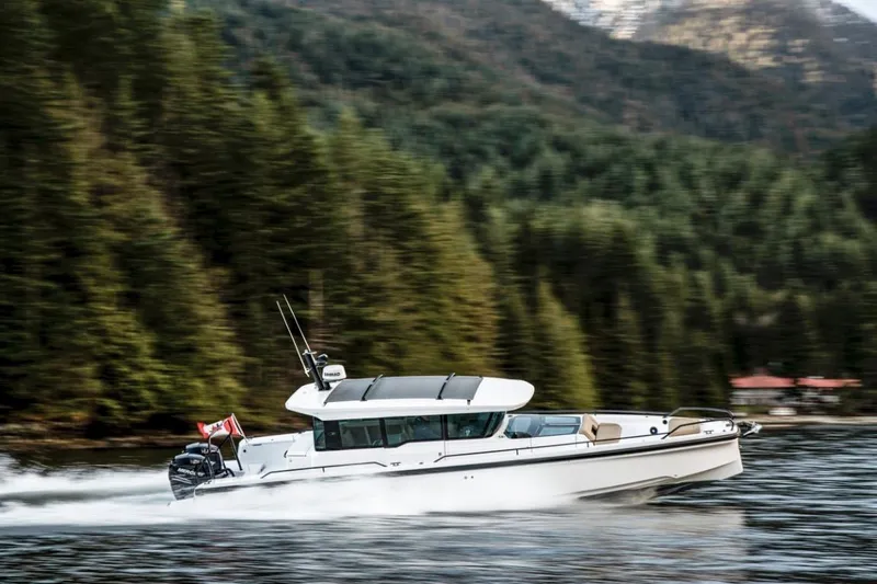  Yacht Photos Pics 2025 Axopar 37XC CROSS CABIN cruising on a scenic forest-lined waterway.