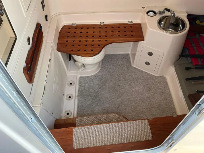 H Lady Frances Yacht Photos Pics 2011 Grady-White Canyon 336 boat interior with toilet, sink, and wooden bench.