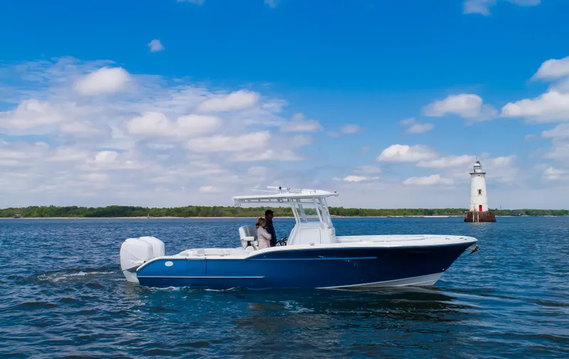  Yacht Photos Pics 2025 Buddy Davis 28 Center Console boat cruising near a lighthouse on a sunny day.