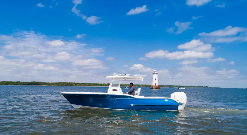  Yacht Photos Pics 2025 Buddy Davis 28 Center Console boat cruising near a lighthouse on a sunny day.
