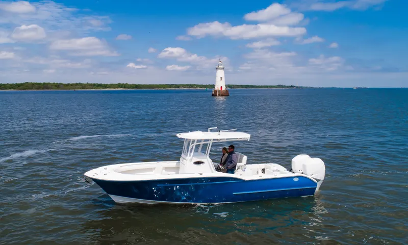  Yacht Photos Pics 2025 Buddy Davis 28 Center Console boat cruising near a lighthouse on a sunny day.