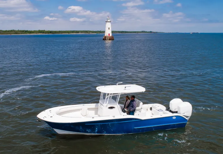  Yacht Photos Pics 2025 Buddy Davis 28 Center Console boat near a lighthouse on a sunny day.