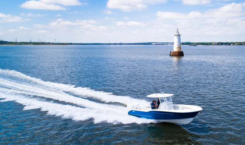  Yacht Photos Pics 2025 Buddy Davis 28 Center Console boat cruising near a lighthouse on open water.