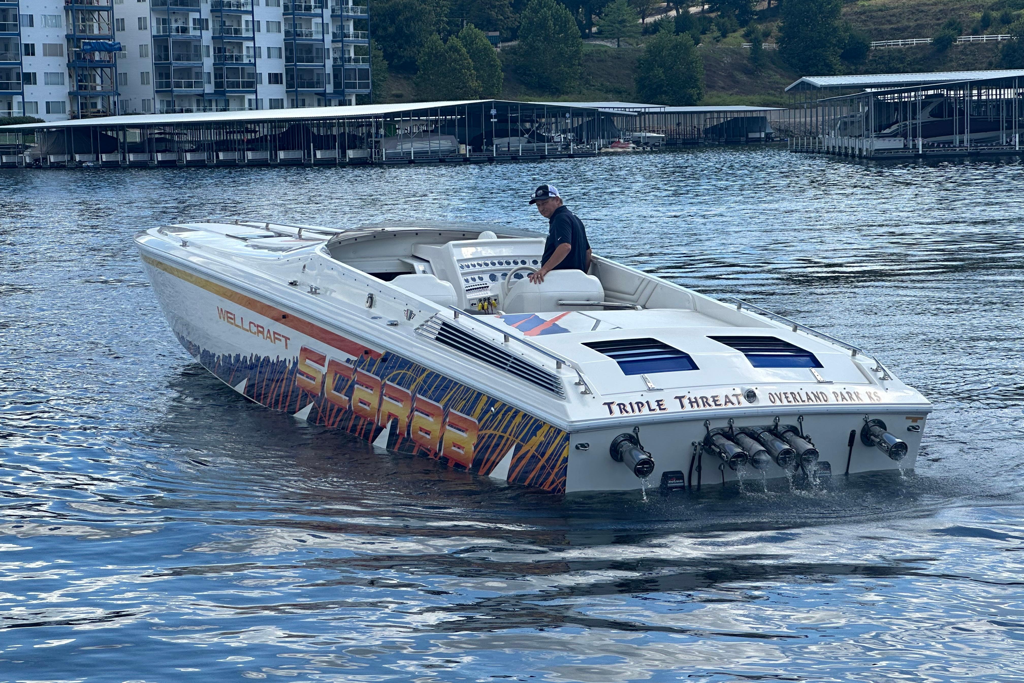 1995 Excel Scarab 43 speedboat on water, featuring vibrant graphics and triple engines.