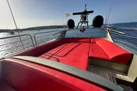 Luxury yacht AB 140, 2011 model, with red seating, anchored in a serene bay.