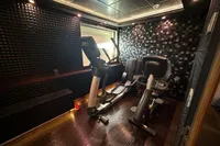 Small home gym with exercise equipment, dark textured walls, and wooden flooring.