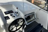 Steering console of 2002 Custom Belter 1240 boat with controls and window.