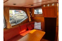 Cozy interior of 2002 Custom Belter 1240 boat with wood paneling and red seating.