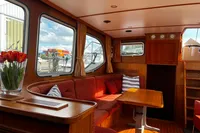 Cozy interior of 2002 Custom Belter 1240 boat with red seating and wooden table.