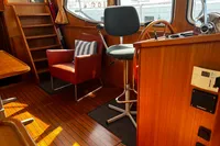 Cozy boat interior with wooden paneling, steering wheel, and seating, Custom Belter 1240, 2002.