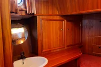 Wood-paneled boat interior with sink, mirror, and storage cabinets, Custom Belter 1240, 2002 model.