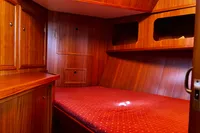 Cozy wooden cabin interior of Custom Belter 1240, 2002 model, with red bedding.