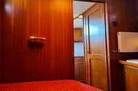 Wood-paneled interior of 2002 Custom Belter 1240 boat with open door and red upholstery.