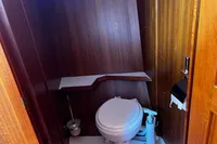 Compact wooden boat bathroom with toilet, shelf, and toilet paper holder, Custom Belter 1240, 2002.