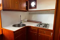 Wooden boat kitchen with sink, gas stove, and porthole window, Custom Belter 1240, 2002.
