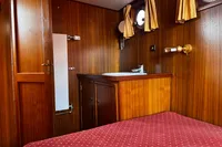 Wood-paneled cabin interior with sink, porthole, and red polka dot bedspread, Custom Belter 1240, 2002.