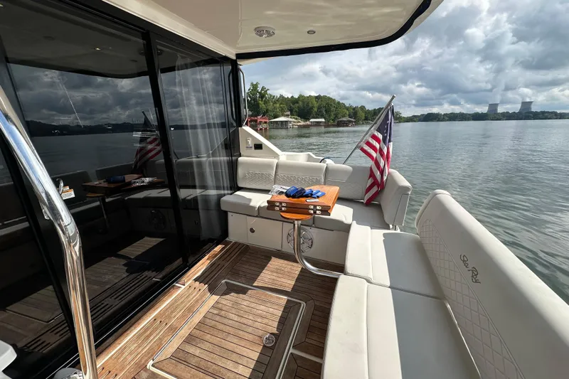  Yacht Photos Pics 2017 Sea Ray Fly 460 yacht deck with seating, table, and American flag on a serene lake.
