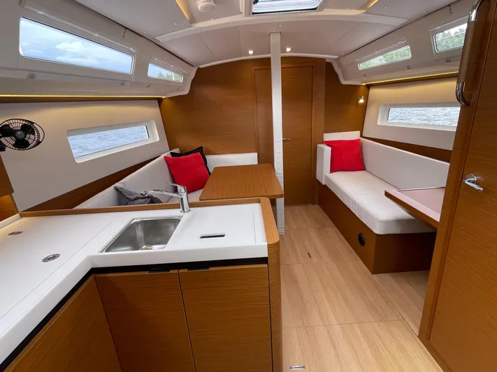  Yacht Photos Pics Interior of 2024 Jeanneau Sun Odyssey 380 sailboat, featuring modern wood finish and cozy seating.