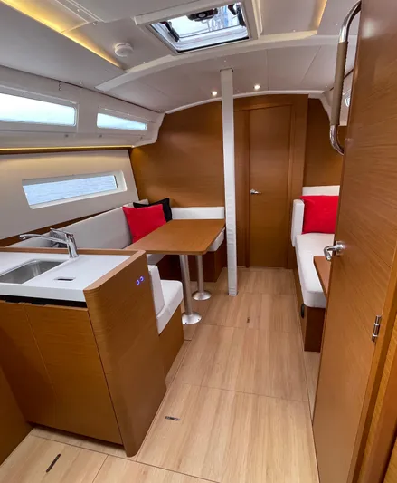  Yacht Photos Pics Interior of 2024 Jeanneau Sun Odyssey 380 yacht with modern wood finish and seating area.