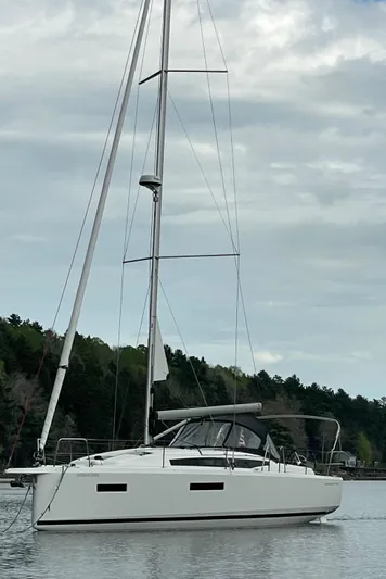  Yacht Photos Pics 2024 Jeanneau Sun Odyssey 380 sailboat on calm water under cloudy sky.