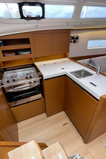  Yacht Photos Pics 2024 Jeanneau Sun Odyssey 380 yacht kitchen with modern appliances and sleek wood cabinetry.