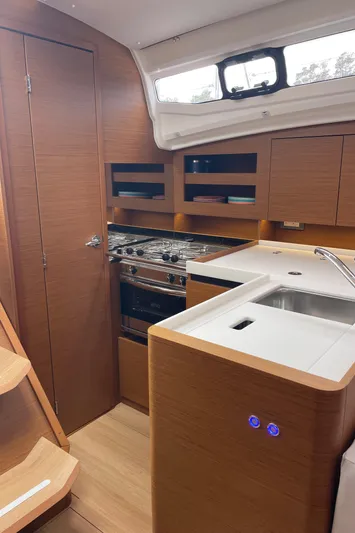  Yacht Photos Pics 2024 Jeanneau Sun Odyssey 380 interior kitchen with modern wood finish and appliances.