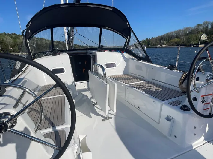  Yacht Photos Pics 2024 Jeanneau Sun Odyssey 380 cockpit with dual steering wheels, sleek design, and scenic water backdrop.