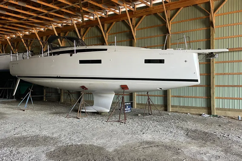  Yacht Photos Pics 2024 Jeanneau Sun Odyssey 380 sailboat in storage, displayed on stands indoors.