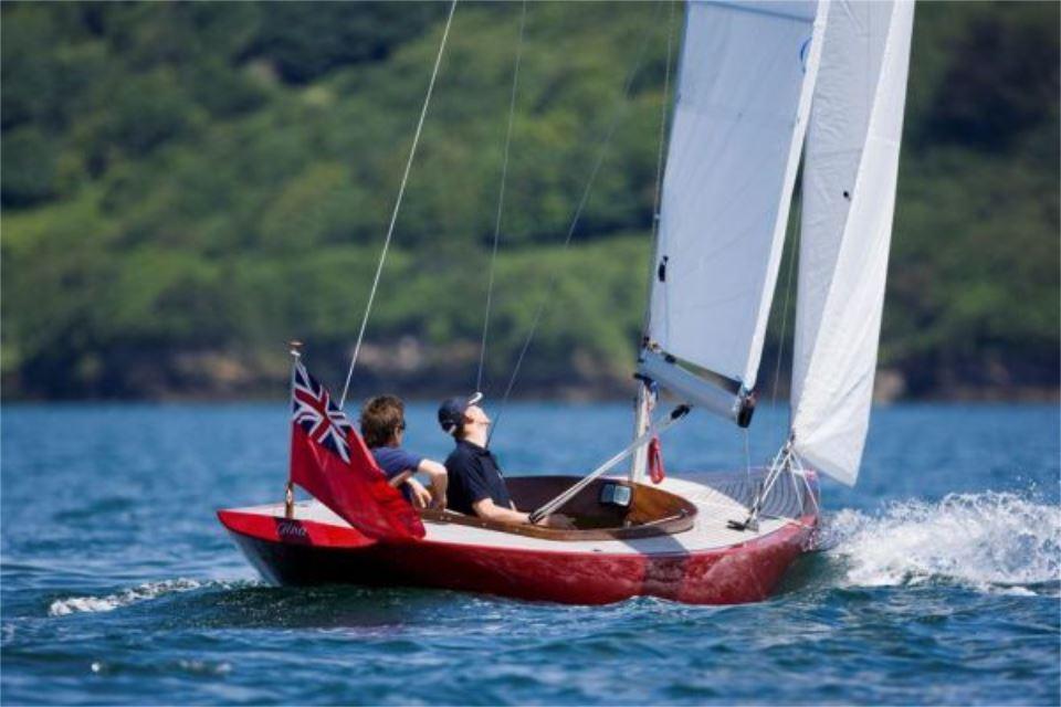 Sailing on a Rustler 24 boat, 2025 model, with vibrant red hull and white sails.