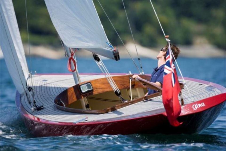 Sailing on a Rustler 24 yacht, 2025 model, with a vibrant red hull and flag.